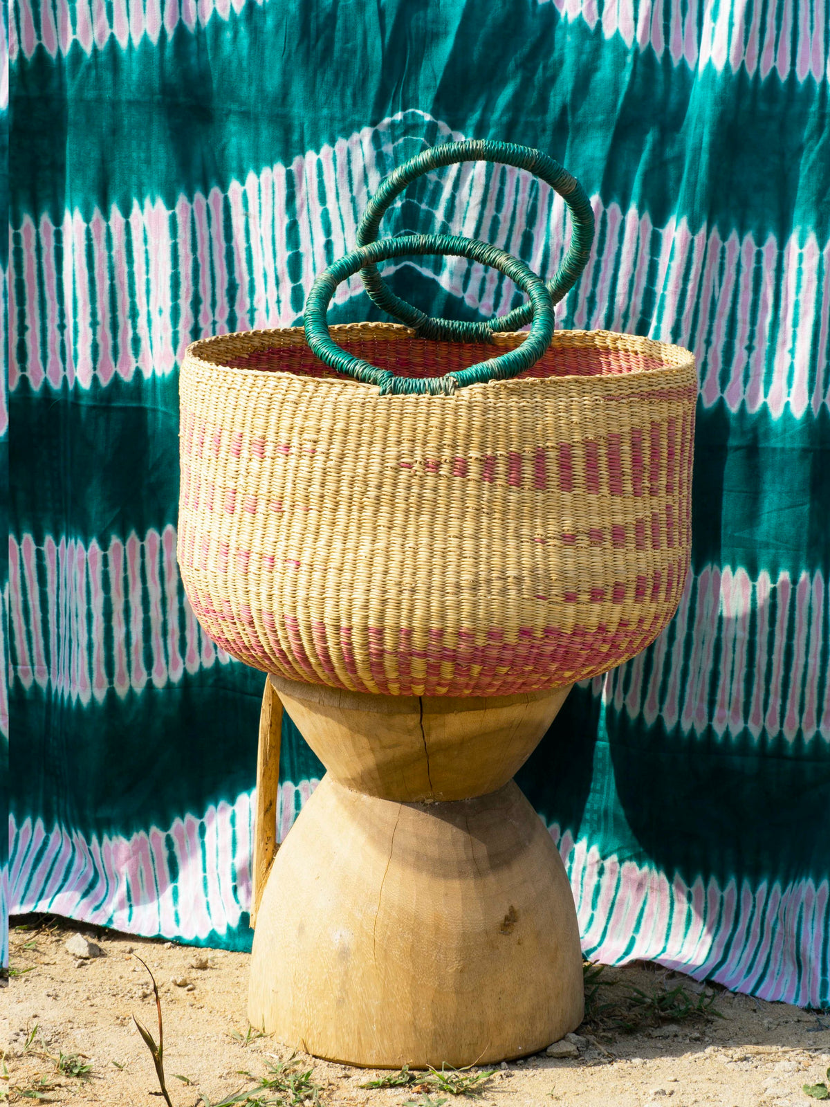 Handwoven storage basket with pink pattern, made from natural grass fibers.