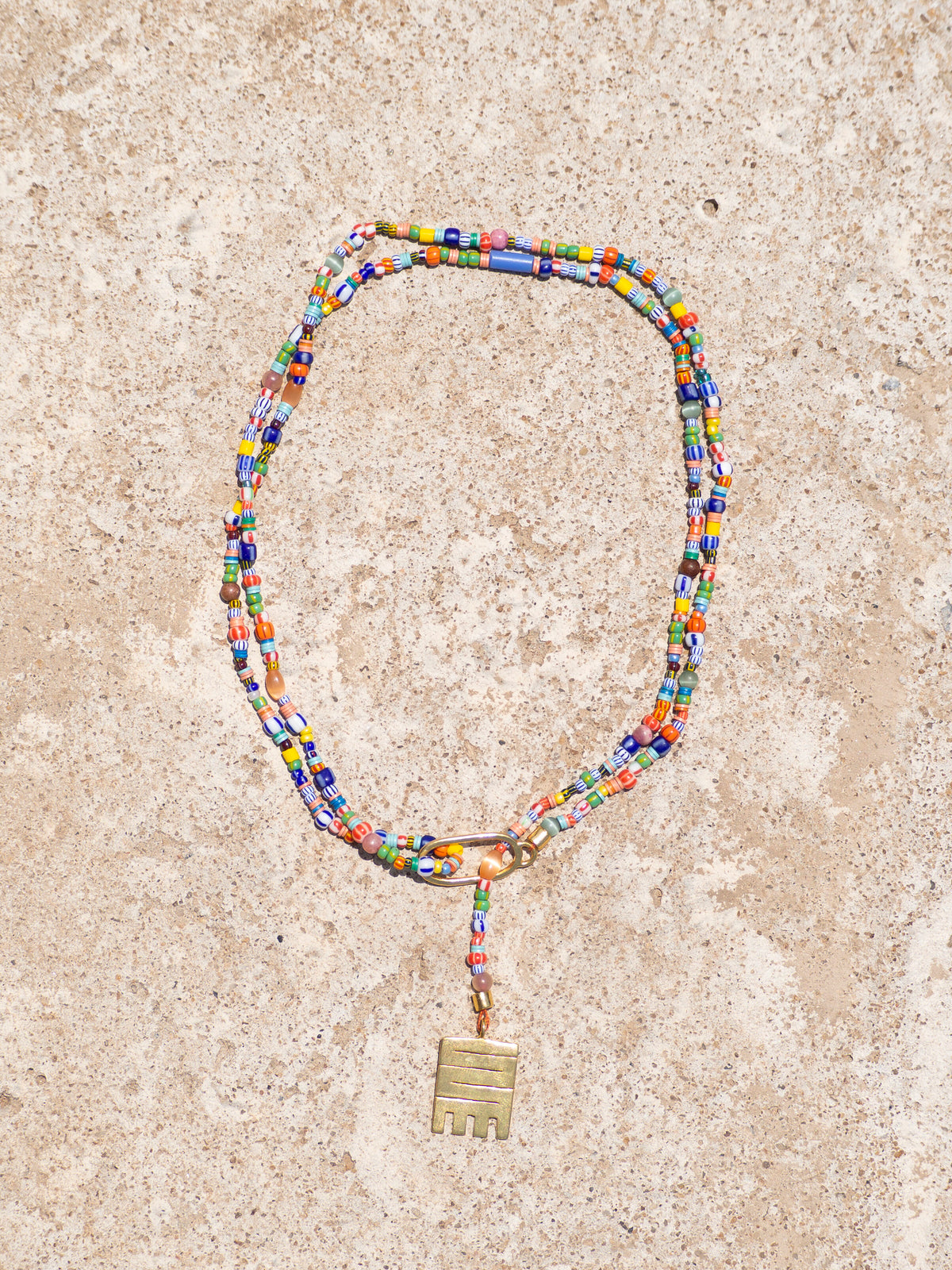 Handmade necklace with colorful recycled glass beads and Adinkra symbol amulet
