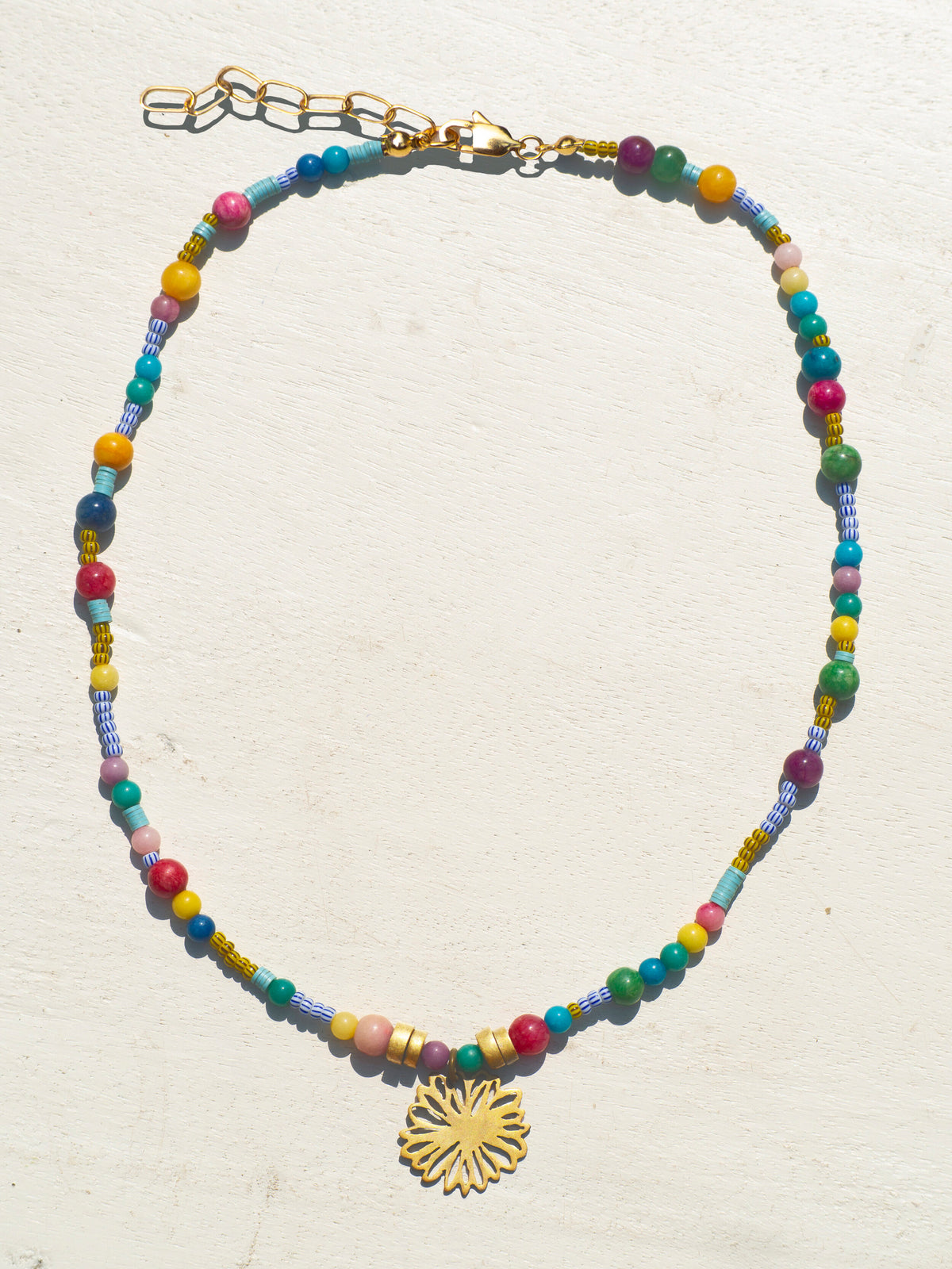 Bohemian-style necklace with african tribe beads and a gold-plated amulet featuring a flower.