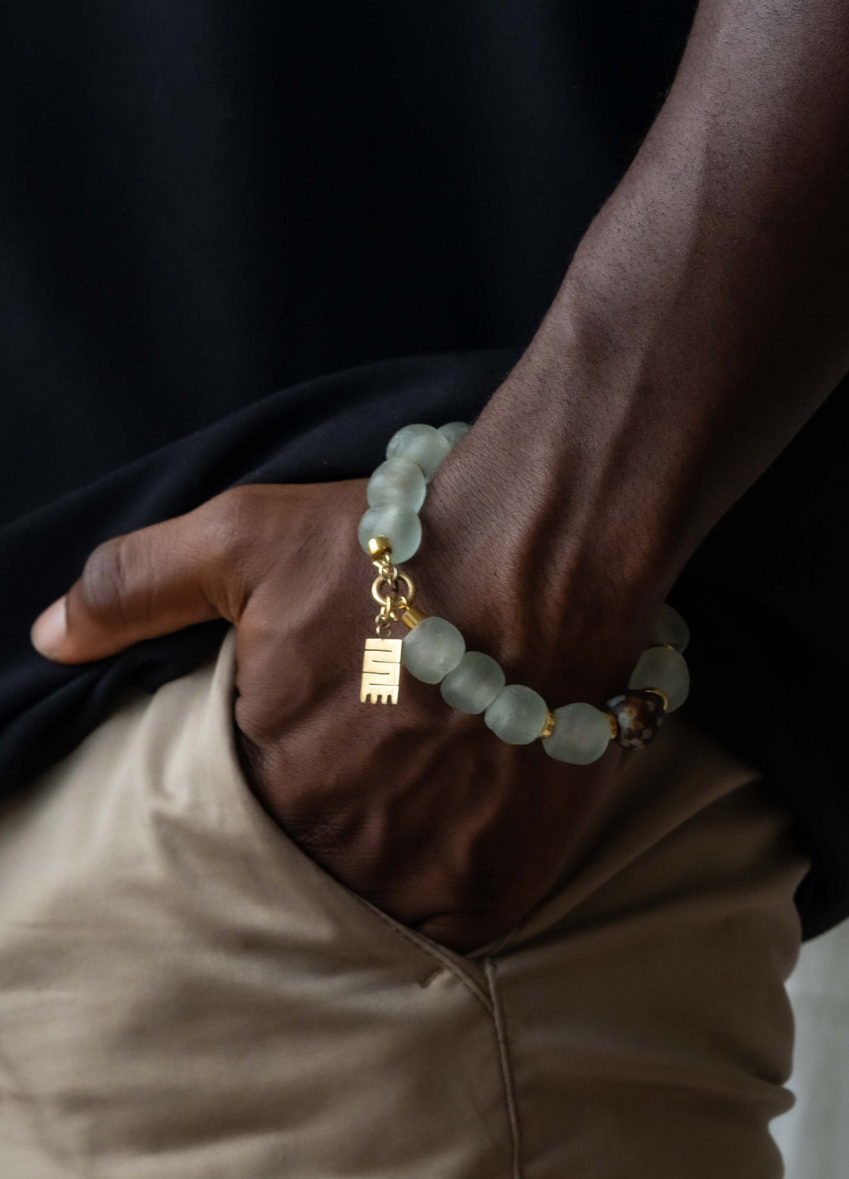 Handcrafted bracelet with rich, multicolored Ghanaian glass beads and gold-plated brass Adinkra symbol amulet
