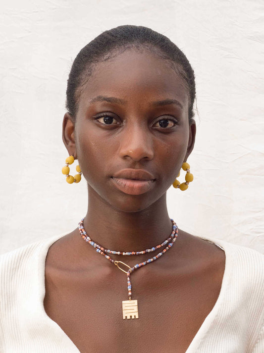 Handmade necklace with nude tones recycled glass beads and Adinkra symbol amulet
